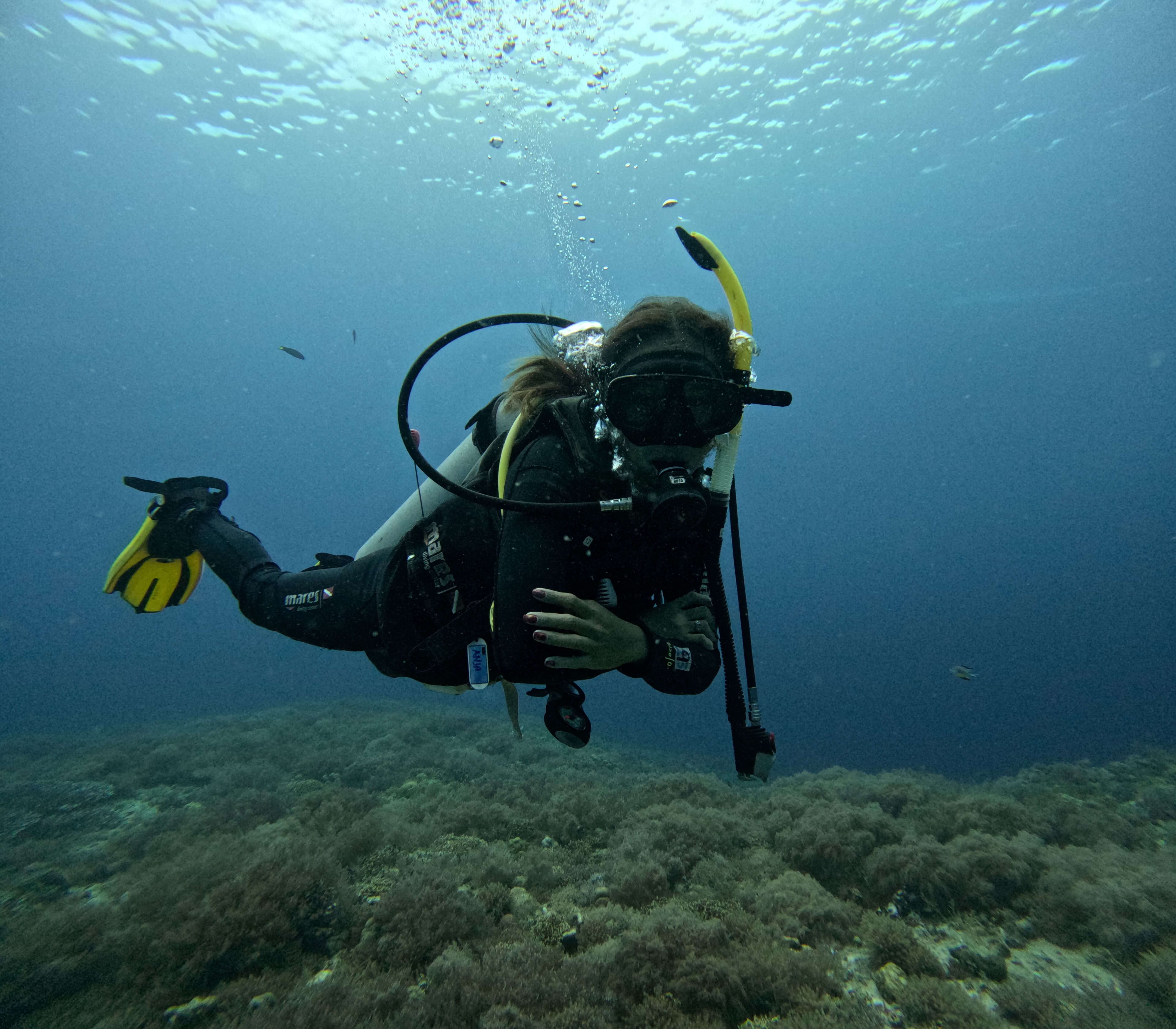 Female scuba diver hovering over coral reef at Malapascua Island, Cebu Philippines